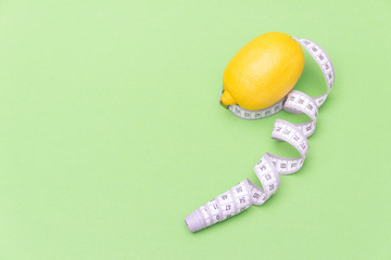 Lemon with measuring meter on green background. Healthy diet concept. Free copy space.