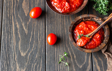 Ajvar (pepper mousse) or pindjur red vegetable spread made from paprika and tomatoes in wooden bowl on the rustic wooden table. Serbian native food.