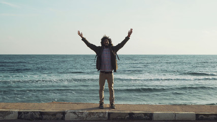 portrait of black male raise hands standing on a road with sea behind