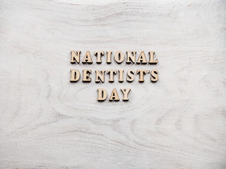 Dentist's day greeting card. White, isolated background, close-up, view from above, wooden surface. Congratulations for relatives, friends and colleagues