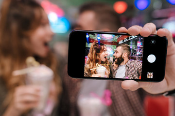 Young loving couple sit in retro bright cafe take a selfie