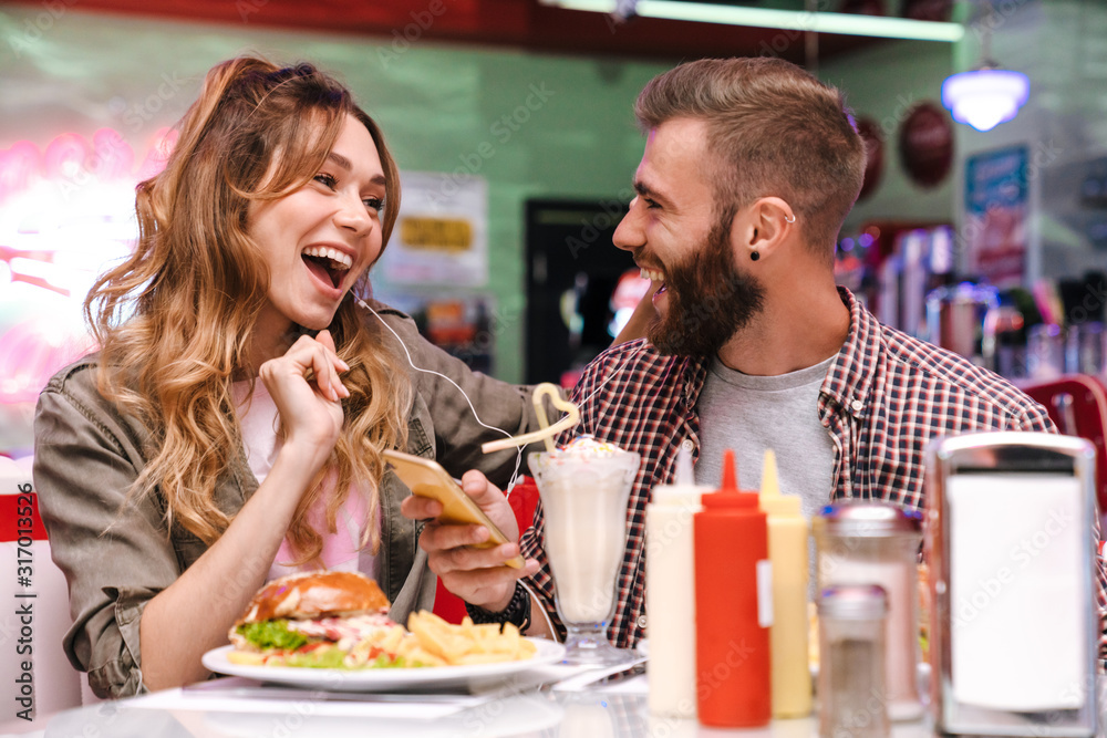 Poster Young loving couple listening music with earphones.