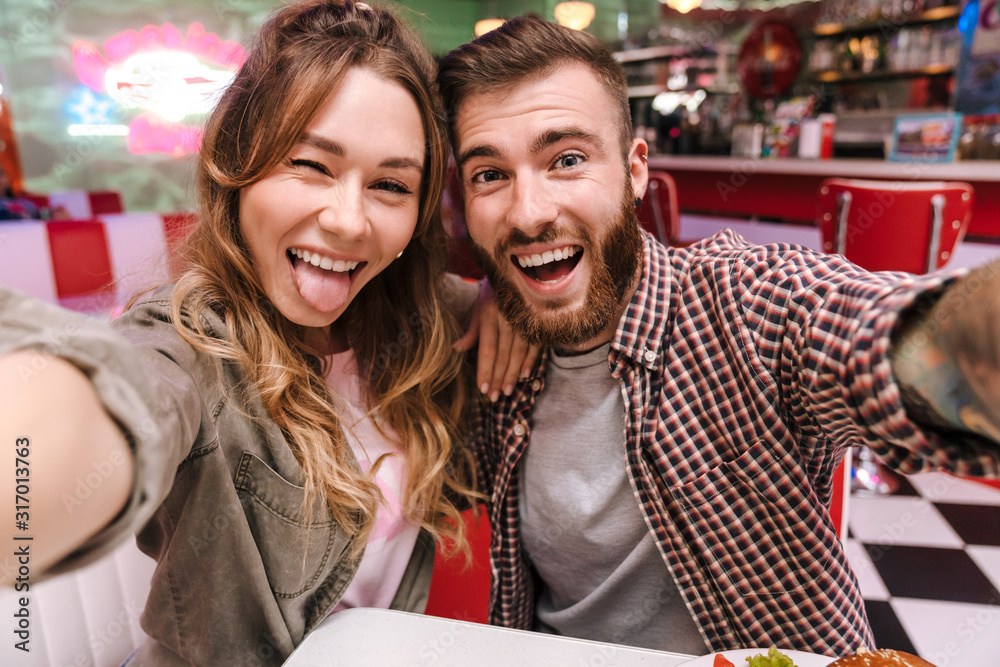 Canvas Prints Couple in retro bright street food cafe take a selfie by camera.