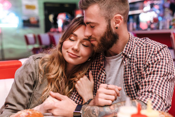 Loving couple in retro bright street food cafe hugging.