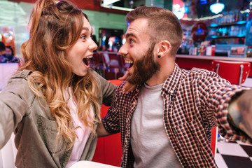 Couple in retro bright street food cafe take a selfie by camera.