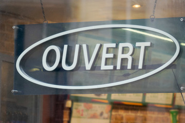 open sign in french means ouvert hanging on the entrance door of a small business concept in france