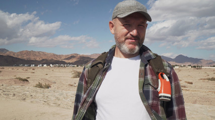 Naklejka premium portrait of handsome senior male standing on a road at desert