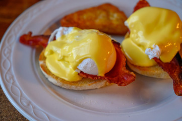 Weekend brunch in Scotland with two eggs benedict on homemade muffuns with roasted bacon and yellow hollandaise sauce.