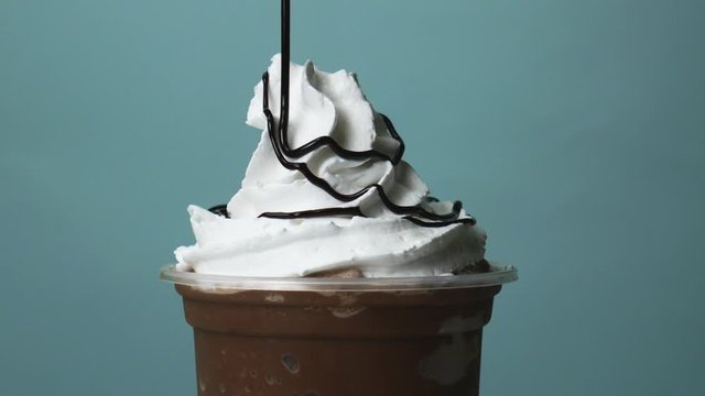 Close up Cocoa smoothie Topped Whip cream Chocolate sauce on blue background, Food concept Front view.