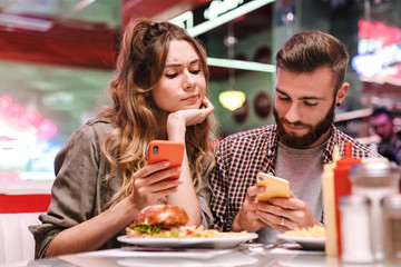 Woman looking at display of her boyfriend's smartphone