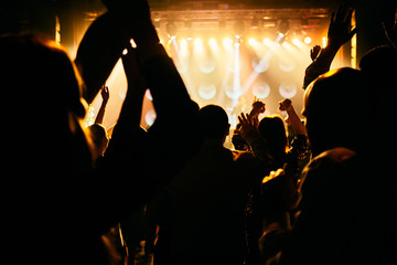 silhouettes of concert crowd in front of bright stage lights
