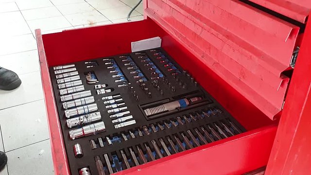 the mechanic in the garage lays out the tools in red metal box, close-up