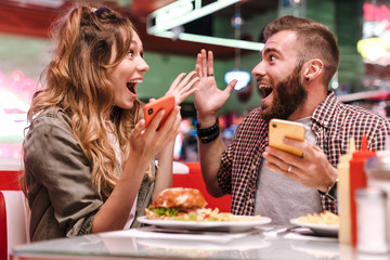 Screaming young loving couple using mobile phones.