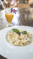 Yummy pasta on cafe table. Closeup plate with portion of tasty pasta with cream sauce placed on table in restaurant