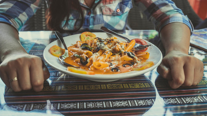 Delicious pasta with tomato sauce. Silverware placed on plate of palatable pasta with tomato sauce and olives on ornamental table in cafeteria