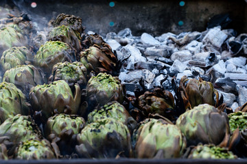 Fototapeta na wymiar Fresh baked artichokes on the coal in the brazier one holiday at the market place.