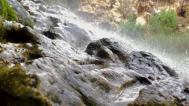 Lluvia de cascada de agua sobre roca salpicando en c&aacute;mara lenta