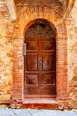 Fototapeta na wymiar Pienza in Tuscany, Italy. View of an architectural detail with ancient wooden door. UNESCO heritage village, famous for the 