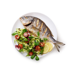 Grilled dorada fish on white plate with fresh salad and lemon pieces. Food photography