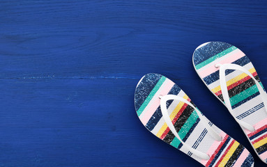 Flip flop in flat style on blue wooden background. Female fashion set.