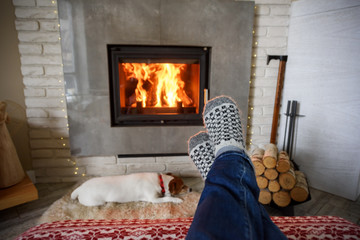Hygge concept with man legs in wool socks near burning fireplace