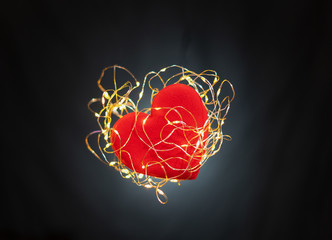 A red heart surrounded by lights on black background,