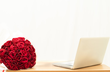 Red rose bouquet and notebook on the table with a white background,
