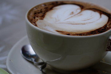 cup of coffee with cream on wooden background