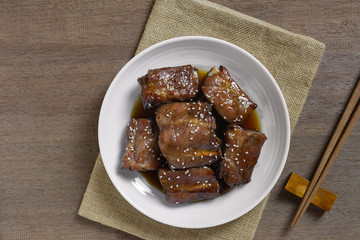 top view of grilled pork rib with teriyaki sauce in a ceramic dish on wooden table. asian homemade style food concept.