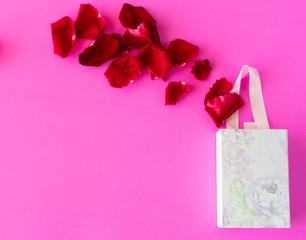 Red Rose petals and gift box on pink color background,
