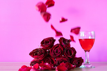 Red roses and red wine glass on the table,