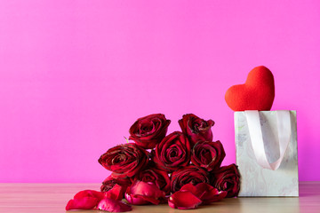 Red Rose petals and gift box on pink color background, red heart on pink background,
