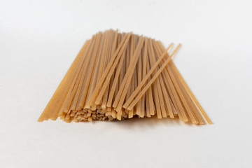 Long flat brown macaroni on a white background.