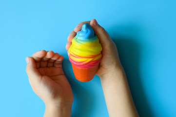 anti stress squishy toy in the form of multicolored ice cream in children's hands on blue background
