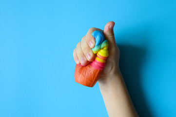 anti stress squishy toy in the form of multicolored ice cream in children's hands on blue background. space for text