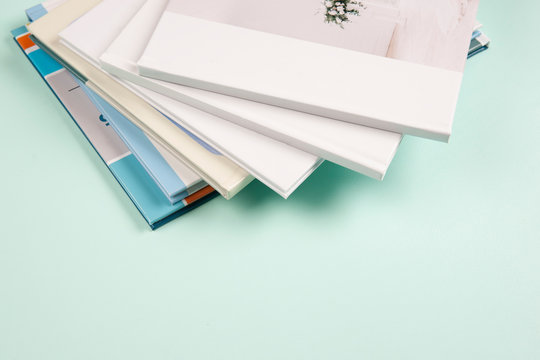 A Stack Of Photo Books And Magazines Lying On A Light Blue Background