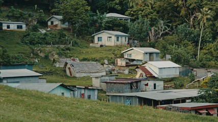 Fototapeta na wymiar beautiful cinematic shot of a remote and isolated southern pacific tropical island village next to the lush rainforest jungle with makeshift buildings and bamboo huts in the bush