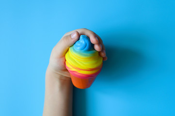 anti stress squishy toy in the form of multicolored ice cream in children's hands on blue background