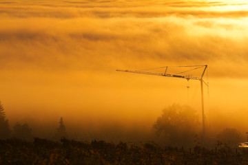 Naklejka premium Construction crane in the fog at sunrise