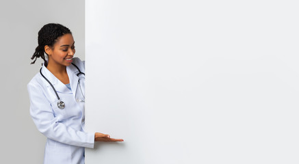 Black female doctor looking and pointing at big blank advertising board