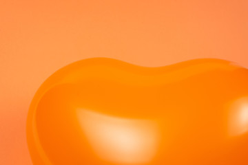 Orange heart ballon on orange background.