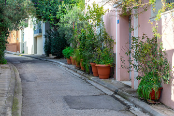 Narrow alley in Plaka Athens old town district. Sidewalk with plants and trees.