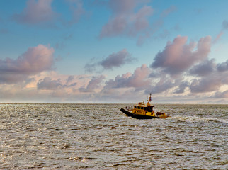 A pilot boat heading out of the harbor in the dawn light