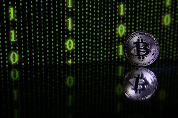 Bitcoin silver coin on the background of green binary code with copy space