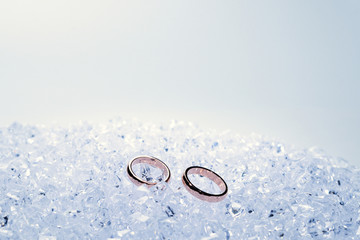 Obraz na płótnie Canvas Two golden wedding rings on ice.