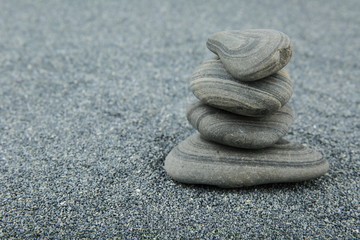 Fototapeta na wymiar background of sea smooth stones. pyramid of stones on gray sand background with free space