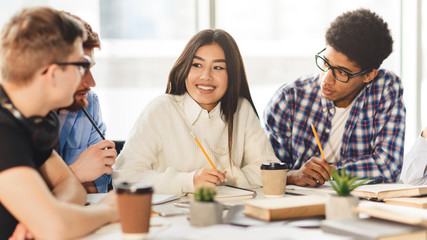 Fototapeta premium Happy multiracial college students studying with books in library