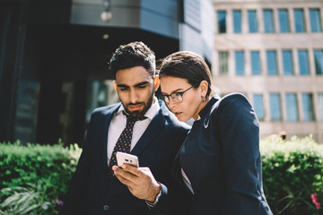 Focused colleagues surfing cellphones in street