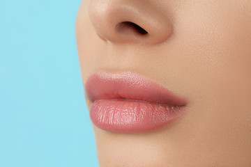 Woman with beautiful full lips on light blue background, closeup