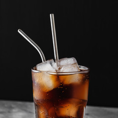 Glass glass with soda and ice ,metal reusable straw for cocktails,close up,black background